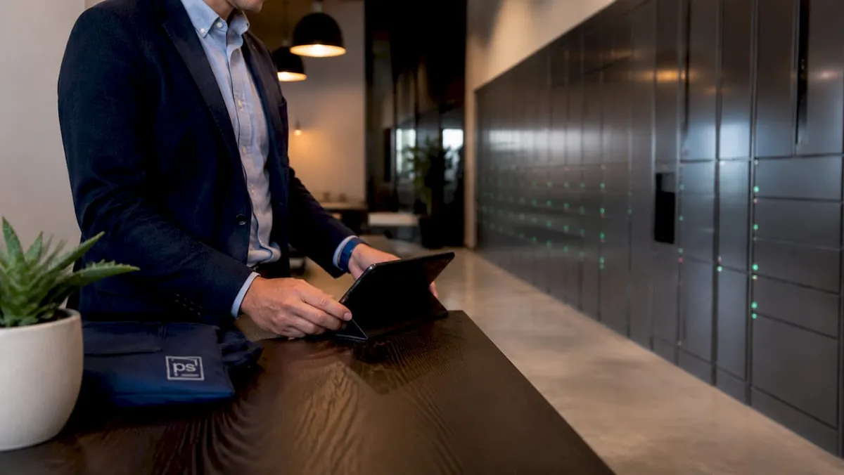 Hands using tablet beside electronic package lockers